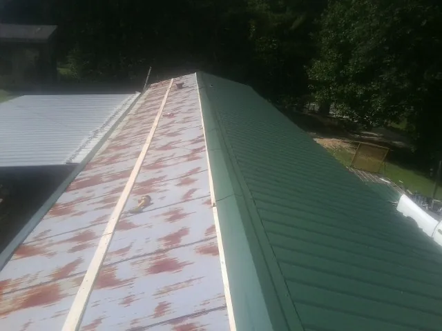 Old rusted panels beside newly installed green metal roofing — Wind Damage Roof Repair by Roofing Brothers in Parksville