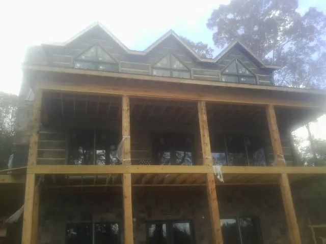 Dormers and porch framing on a large log home under construction — Roof Coating work by our crew in Parksville